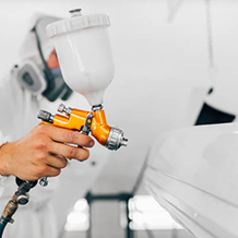Spray painter refinishing a vehicle panel